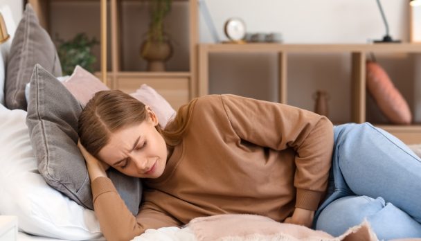 Young,Woman,With,Appendicitis,Lying,In,Bedroom